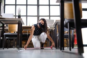 women wearing face covering measuring the distance between desks in office