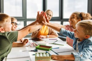 Students in a kids classroom high fiving each other. 